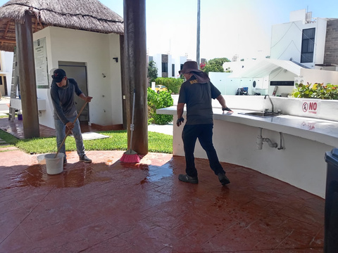 Personal lavando el piso de la palapa